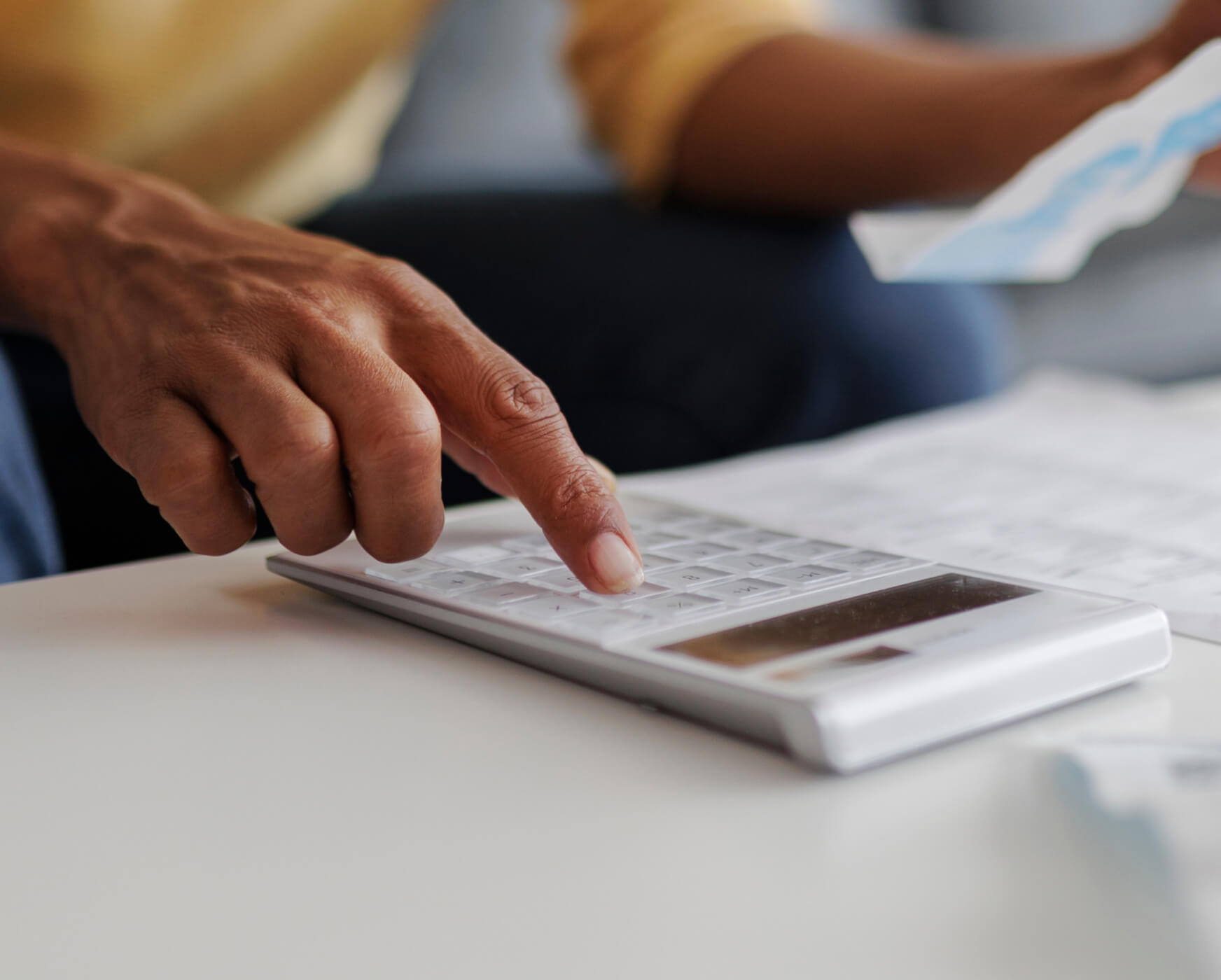 Person calculating with a white calculator and documents.