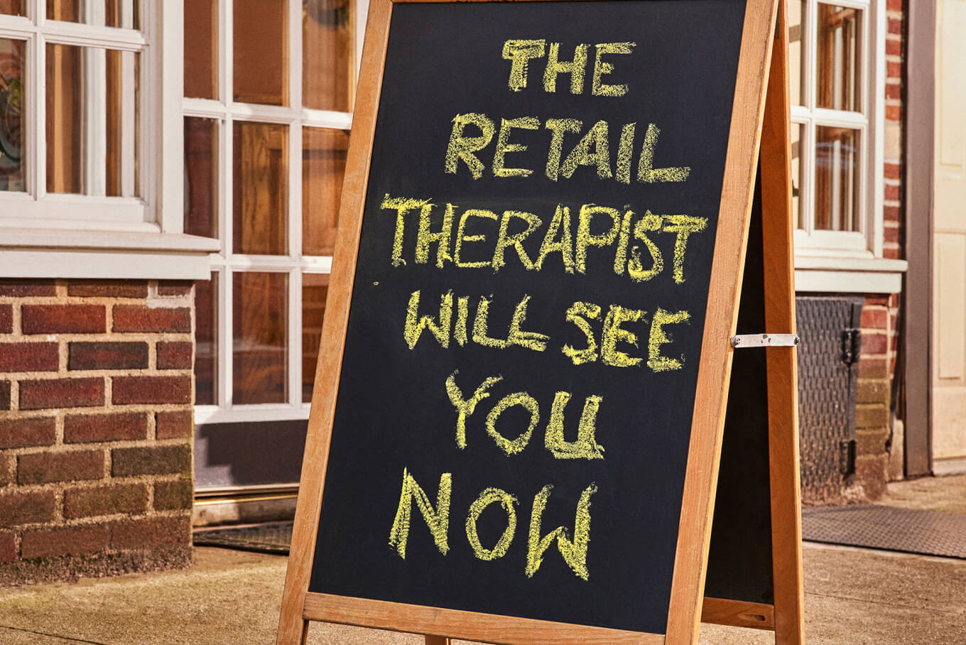 A blackboard with chalk writing that says the retail therapist will see you now.